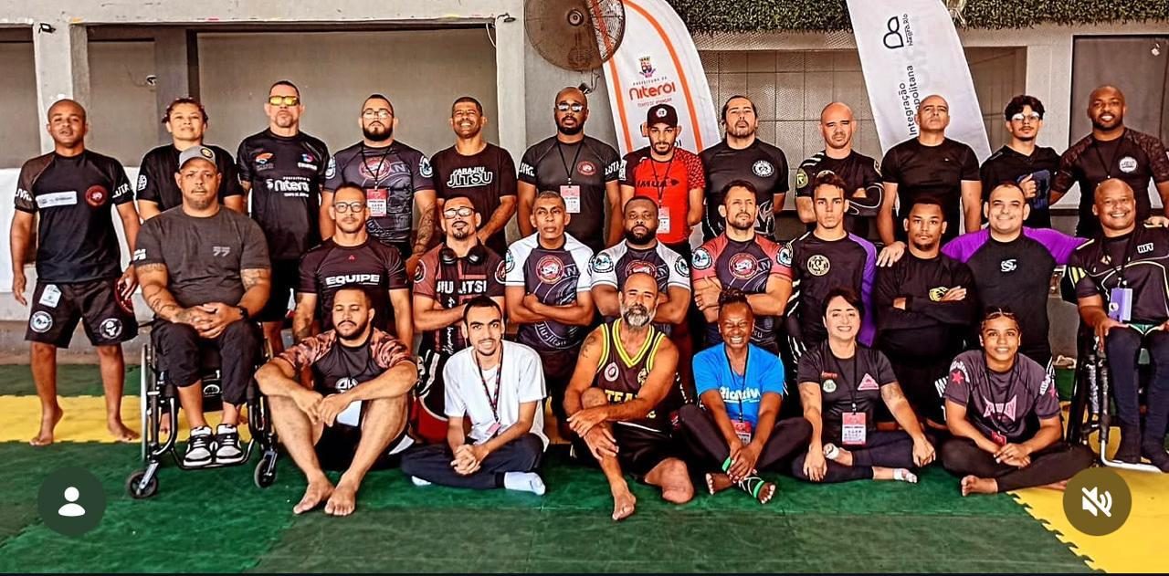 Atletas e professores de jiu-jitsu reunidos sobre o tatame em um evento em Niterói, entre eles atletas em cadeira de rodas.